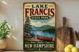 A vintage-style sign for Lake Francis State Park in New Hampshire, featuring a scenic image of a lake, mountains, and a canoe.