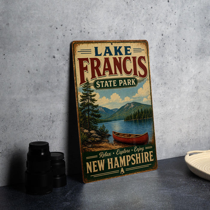 A vintage-style metal sign for Lake Francis State Park in New Hampshire, featuring a scenic image of a lake with a canoe and mountains in the background.