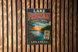 A vintage metal sign for Lake Frieson State Park in Arkansas, featuring a scenic landscape with a sunset over the lake and trees in the background.