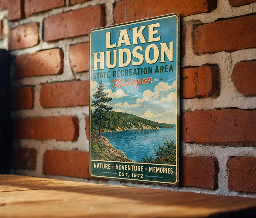A vintage metal sign for Lake Hudson, the Lake Hudson Recreation Area in Michigan, is displayed on a brick wall.