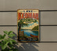 A vintage-style metal sign for Lake Keomah State Park in Iowa, featuring a scenic illustration of the lake and surrounding landscape.