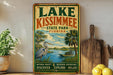 A vintage-style sign for Lake Kissimmee State Park, Florida, featuring a seagull, palm trees, and a body of water.