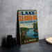 A vintage-style sign for Lake Le-Aqua-NA, a state recreation area in Illinois, featuring a scenic image of a lake with boats and people fishing.