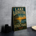 A vintage-style sign for Lake Livingston State Park in Texas, featuring a scenic landscape with a sunset over the lake and a bird in flight.