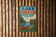 A vintage-style metal sign for Lake Loramie State Park in Ohio, featuring a scenic image of a lake, canoe, and surrounding nature.