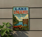 A vintage-style metal sign for Lake Loramie State Park in Ohio, featuring a canoe and a scenic landscape.