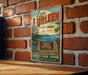 A vintage-style metal sign for Lake Lurry State Park in Alabama, featuring a scenic illustration of the park and a message encouraging visitors to "Recreate, Relax, Refresh" and "Make Memorable Memories That Last".