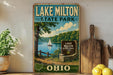 A vintage-style sign for Lake Milton State Park in Ohio, featuring a scenic landscape with a lake, trees, and a sailboat.