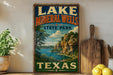 A vintage-style sign for Lake Mineral Wells State Park in Texas, featuring a scenic landscape with a lake, mountains, and trees.