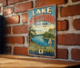 A vintage-style metal sign for Lake Murphy'sboro State Park in Illinois, featuring a scenic illustration of a lake surrounded by trees and a sailboat.