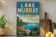 A vintage-style sign for Lake Murray State Park in Oklahoma, featuring a scenic illustration of the lake and surrounding landscape.