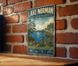 A vintage-style metal sign for Lake Norman State Park in North Carolina, featuring a scenic illustration of a lake, trees, and a sailboat.