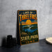 A vintage-style metal sign for Lake of Three Fires State Park in Iowa, featuring a scenic landscape with a sunset over a lake and mountains.