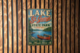 A vintage metal sign for Lake St. George State Park in Maine, featuring a canoe and a scenic landscape.