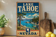 A vintage-style sign for Lake Tahoe, Nevada State Park, featuring a scenic landscape with a lake, mountains, and pine trees.