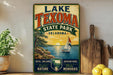 A vintage-style sign for Lake Texoma State Park in Oklahoma, featuring a sailboat on a lake and a sunset in the background.