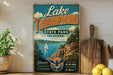 A vintage-style sign for Lake Thunderbird State Park in Oklahoma, featuring a scenic illustration of a lake, mountains, and a sailboat.