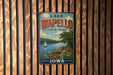 A vintage metal sign for Lake Wapelo State Park in Iowa, featuring a scenic landscape with a lake, sailboat, and surrounding trees.