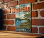 A vintage-style metal sign for Lake Wapollo State Park in Iowa, featuring a scenic illustration of a lake, sailboat, and surrounding landscape.