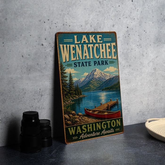 A vintage-style metal sign for Lake Wenatchee State Park, featuring a scenic illustration of a lake, mountains, and a canoe.
