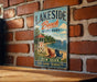 A vintage metal sign for Lakeside Beach State Park, featuring a lifeguard tower, beach chairs, and a scenic view of the ocean.