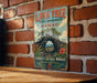 A vintage-style metal sign for the Lava Tree State Monument in Hawaii, featuring a scenic illustration of a lava flow and tropical foliage.