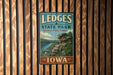 A vintage-style metal sign for LEDGES STATE PARK in Iowa, featuring a scenic image of a cliff overlooking a river.