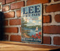 A vintage-style metal sign for Lee State Park in South Carolina, featuring a scenic illustration of a lake, pier, and sailboat.