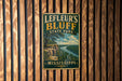 A vintage metal sign for Leffeur's Bluff State Park in Mississippi, featuring a scenic landscape with a river and cliffs.