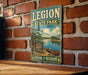 A vintage-style metal sign for Legion State Park in Mississippi, featuring a scenic illustration of a lake, trees, and a canoe.