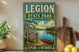 A vintage-style sign for Legion State Park in Mississippi, featuring a scenic illustration of a lake, trees, and a canoe.