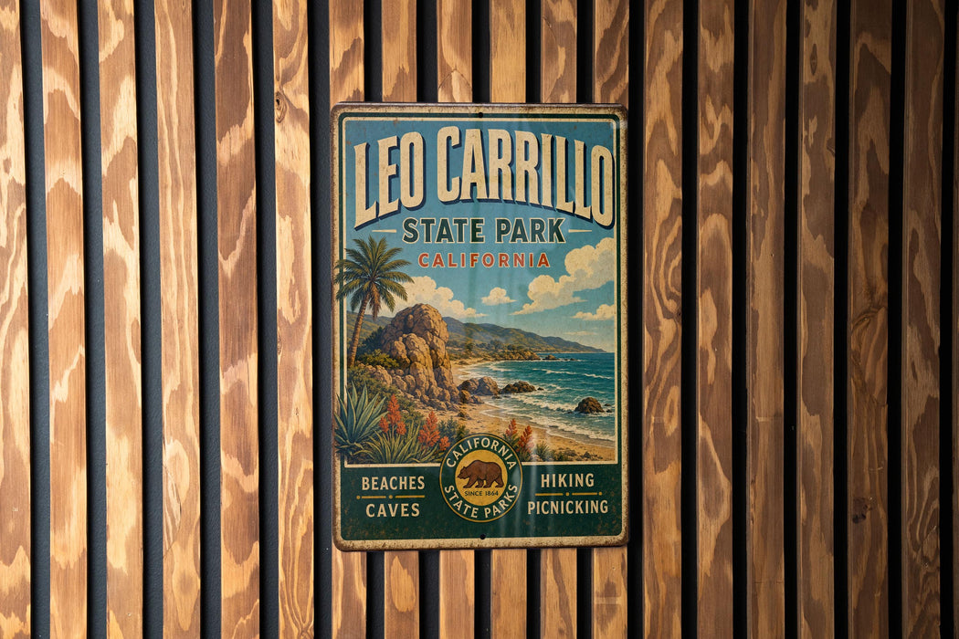 A vintage-style metal sign for Leo Carrillo State Park in California, featuring a beach, palm trees, and mountains.