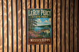 A vintage-style metal sign for LeRoy Percy State Park in Mississippi, featuring a scenic landscape with a wooden bridge, trees, and a lake.