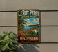 A vintage metal sign for LeRoy Percy State Park in Mississippi, featuring a scenic landscape with a wooden dock, trees, and a lake.