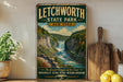 A vintage-style sign for Litchworth State Park in New York, featuring a scenic image of a waterfall surrounded by lush greenery.