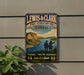 A vintage-style metal sign for the Lewis and Clark State Recreation Area in Nebraska, featuring a scenic landscape with two figures exploring the area.