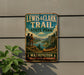 A vintage-style metal sign for Lewis & Clark Trail State Park, featuring an illustration of two men standing on a cliff overlooking a river with a canoe, surrounded by mountains and forests.