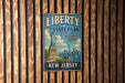 A vintage metal sign with the text "LIBERTY STATE PARK" and "FREEDOM AWAITS" hangs on a wooden wall.