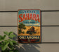 A vintage-style metal sign for Little Sahara State Park in Oklahoma, featuring an illustration of a person riding an ATV in a desert landscape.