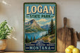 A vintage-style sign for Logan State Park, featuring a scenic mountain landscape with a lake and pine trees, is displayed on a shelf next to a wooden cutting board and some lemons.