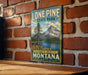A vintage-style metal sign for Lone Pine State Park, featuring a scenic mountain landscape and a lake, is displayed on a brick wall.