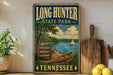A vintage-style sign for Long Hunter State Park in Tennessee, featuring a scenic image of a lake, a sailboat, and a sign indicating the park's outdoor adventure, natural beauty, and lasting memories.