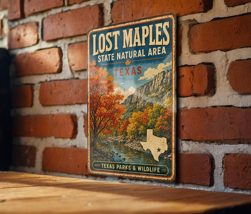A vintage-style metal sign for Lost Maples State Natural Area in Texas, featuring a scenic landscape with autumn trees and a river.