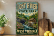 a vintage-style sign for Lost River State Park in West Virginia, with a scenic illustration of a river, forest, and a mill.