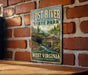 A vintage-style sign for Lost River State Park in West Virginia, featuring a scenic illustration of a river, cabin, and mountains.
