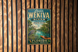 A vintage metal sign for Lower Wekiva River Preserve State Park in Florida, featuring an illustration of a bird and a canoe on a river surrounded by lush greenery.