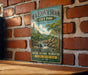 A vintage-style metal sign for Macadonia Brook State Park in Connecticut, featuring a scenic illustration of a waterfall and forest.