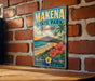 A vintage-style metal sign for Makena State Park in Hawaii, featuring a tropical beach scene with palm trees, flowers, and a mountain in the background.