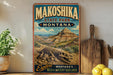 A vintage-style poster advertising Makoshika State Park in Montana, featuring a dinosaur skeleton and a mountainous landscape.