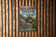A vintage metal sign for Malakoff Diggers State Historic Park in California, featuring a scenic image of a gold mining operation.